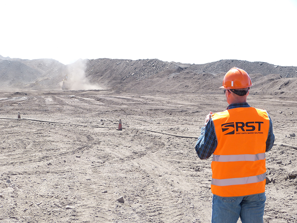 An RST operative monitors dust from a truck on a haul road