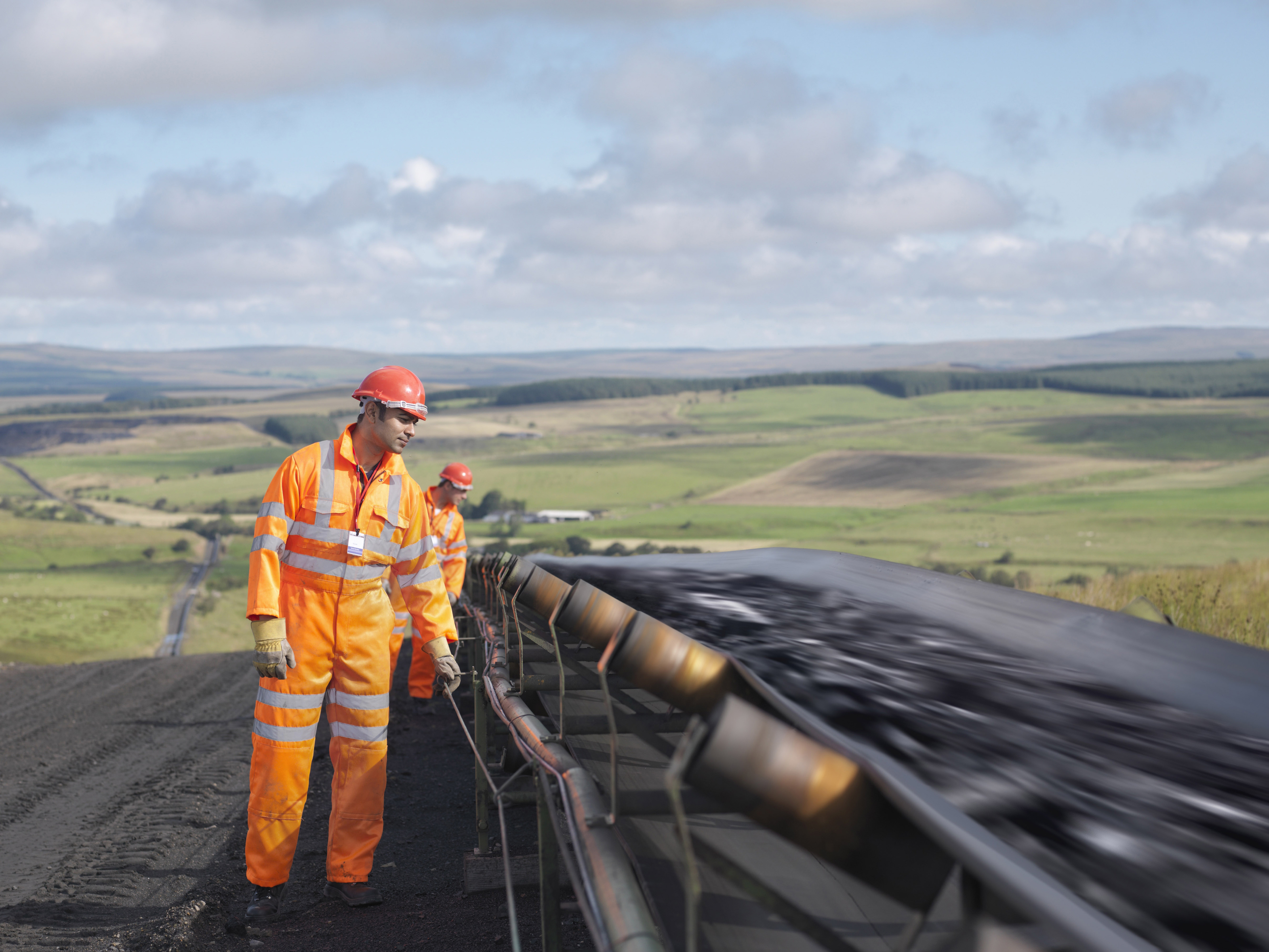 Two workmen inspecting a conveyor belt