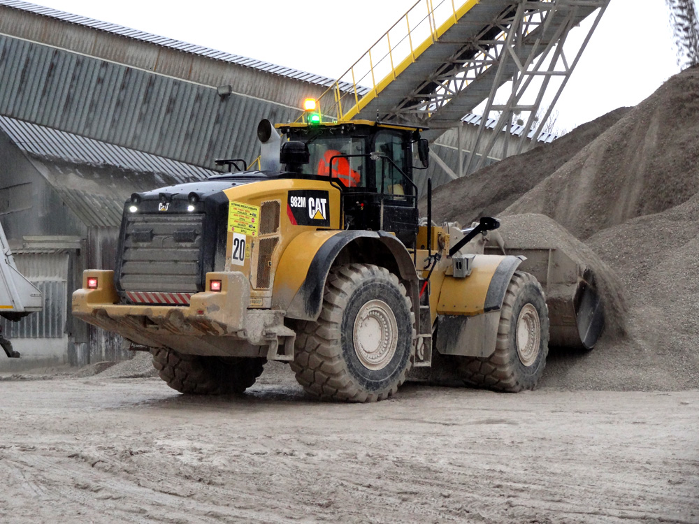 A Cat 982M wheeled loader digs into stockpiled material