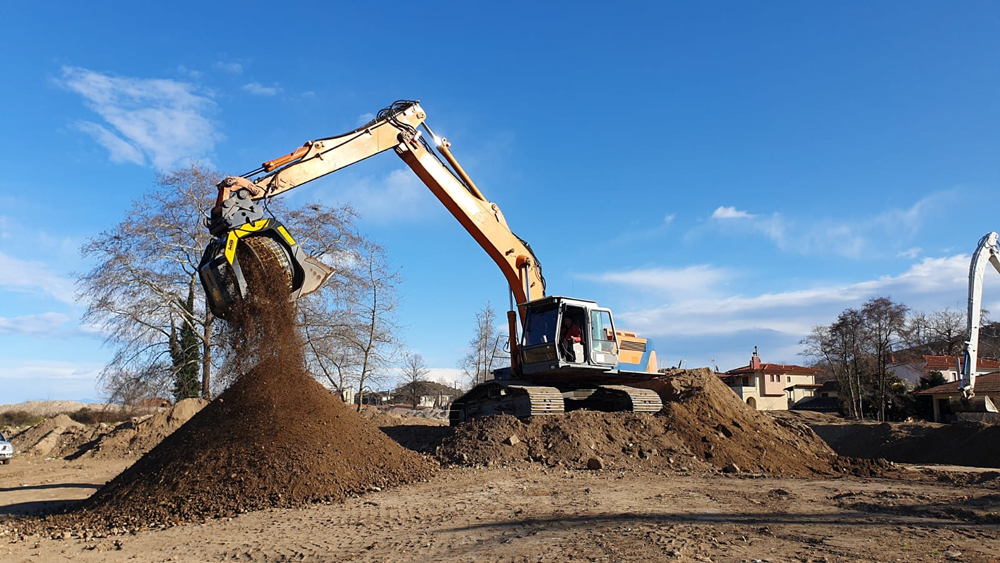 An MB Crusher’s MB-S18 rotary screening bucket attached to a Caterpillar excavator separates soil from small rocks during a cost-efficient riverbed protection project in Greece