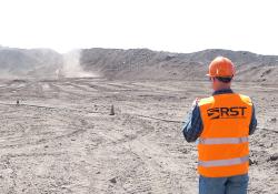 An RST operative monitors dust from a truck on a haul road