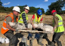 Members of the archeological team lifting a mammoth tusk found at the quarry site. Image: DigVentures