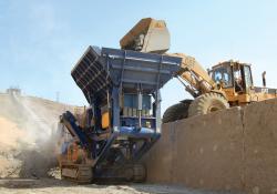 Cat loader putting minerals into a sandvik QJ330 jaw crusher