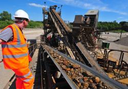 Quarry worker standing by conveyors in operation