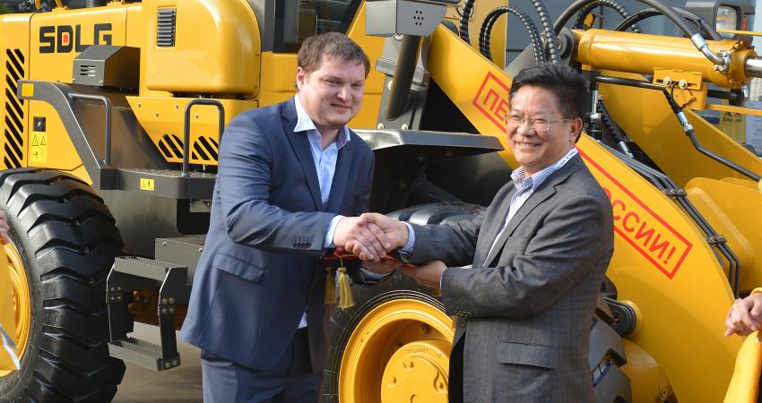 Zhi Kaiying from SDLG shakes hands with Alexey Sharin, 