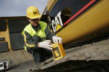 Cat employee replacing a part on a Cat machine